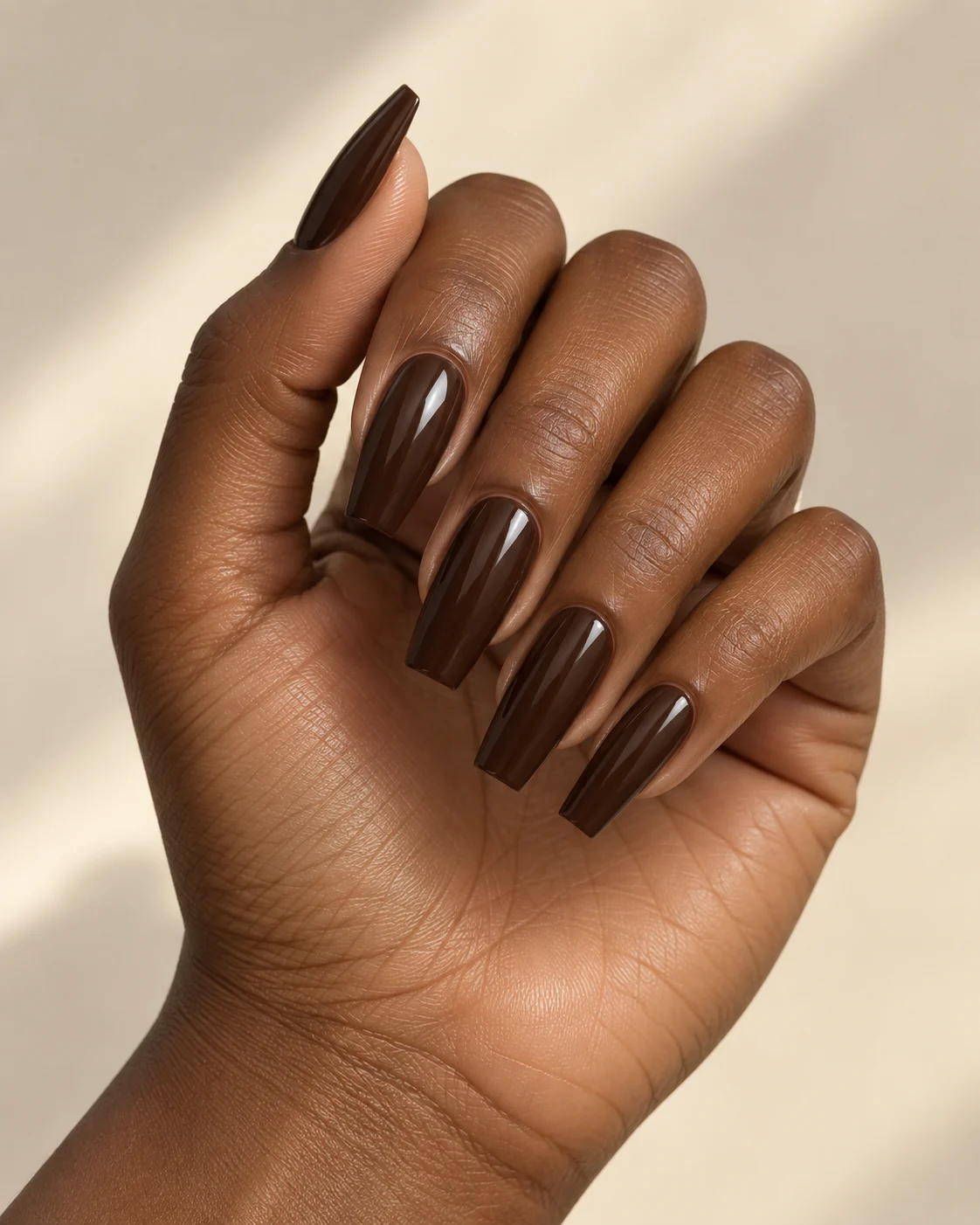 Uñas largas de punta cuadrada con esmaltado marrón brillante.